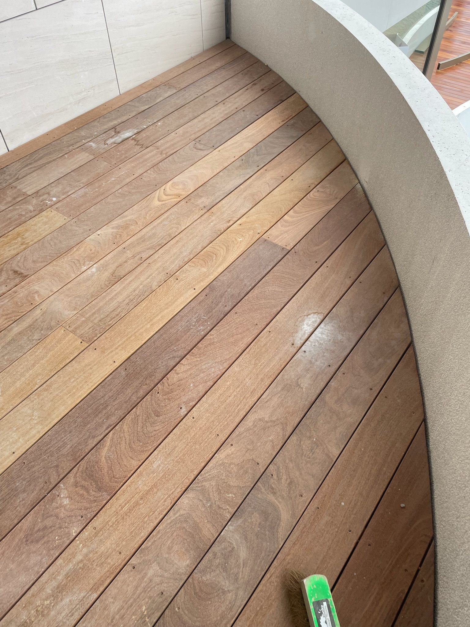 Detail van hardhouten terrasplanken die strak een gebogen borstwering volgen in Deinze