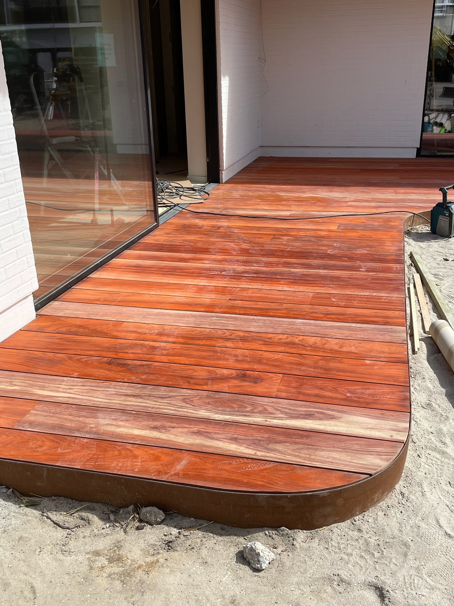 Hardhouten terras met een afgeronde hoek langs een glazen gevel in Knokke-Heist