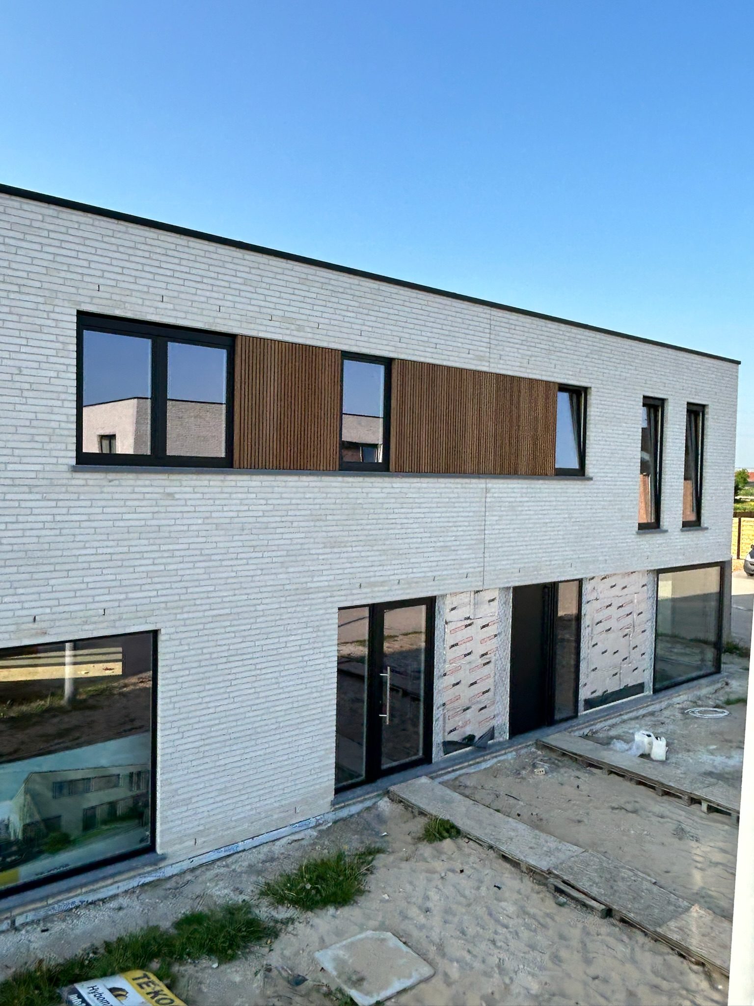 Nieuwbouw met houten gevelbekleding tussen lichte baksteen in Ardooie
