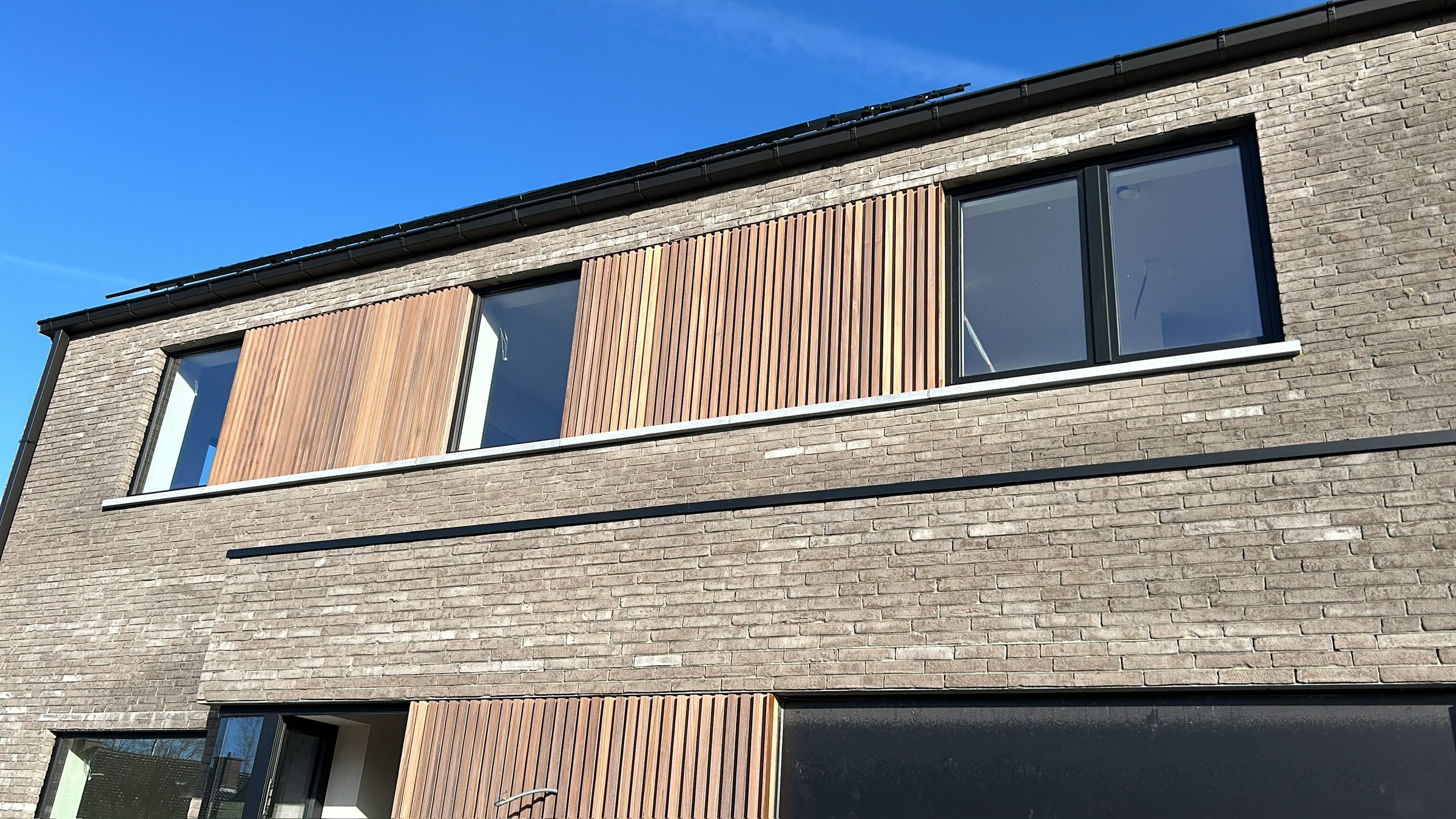 Houten gevelbekleding tussen grijze baksteen