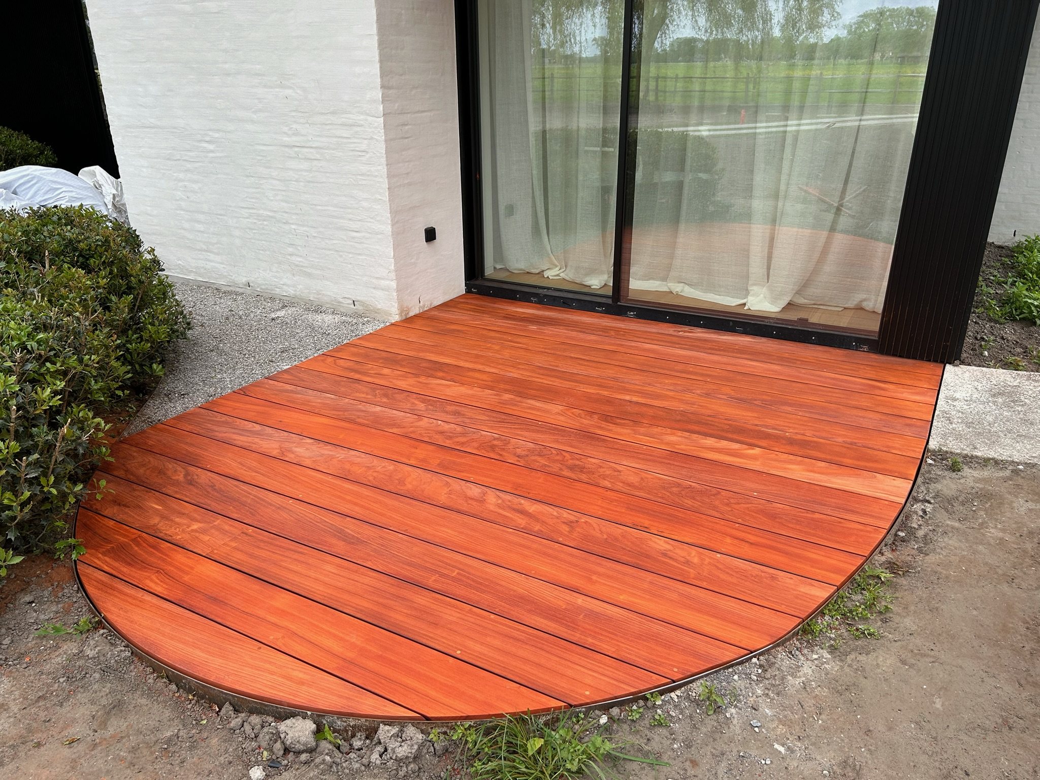Rond hardhouten terras voor een schuifraam in Oostkerke