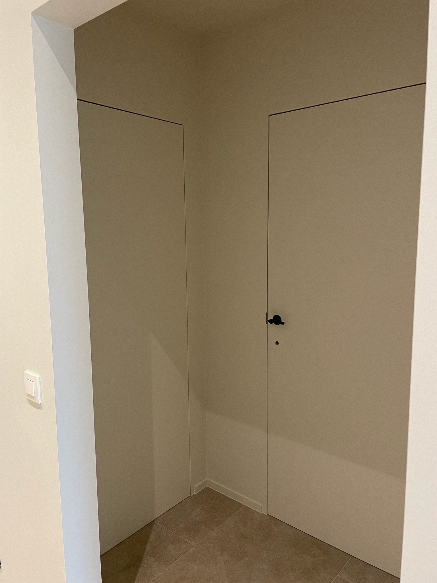 Verdoken binnendeur vlak in de wand met zwarte klink in Meulebeke