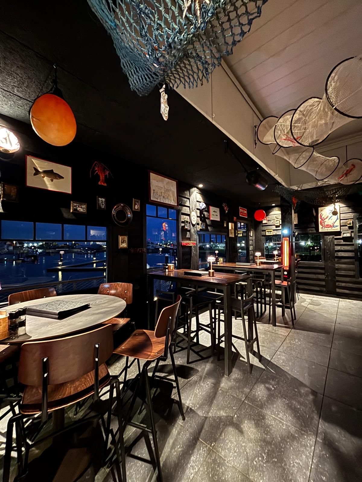 Interieur van restaurant 't Werftje met zwarte houten wanden en zicht op de jachthaven van Zeebrugge