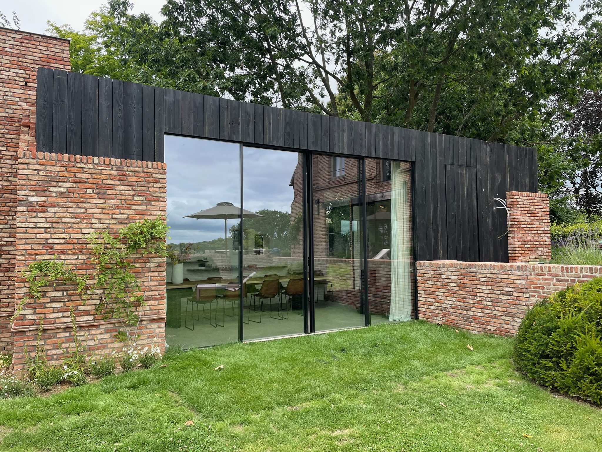 Baksteenwoning met zwarte houten bekleding aan de tuinzijde in Meise
