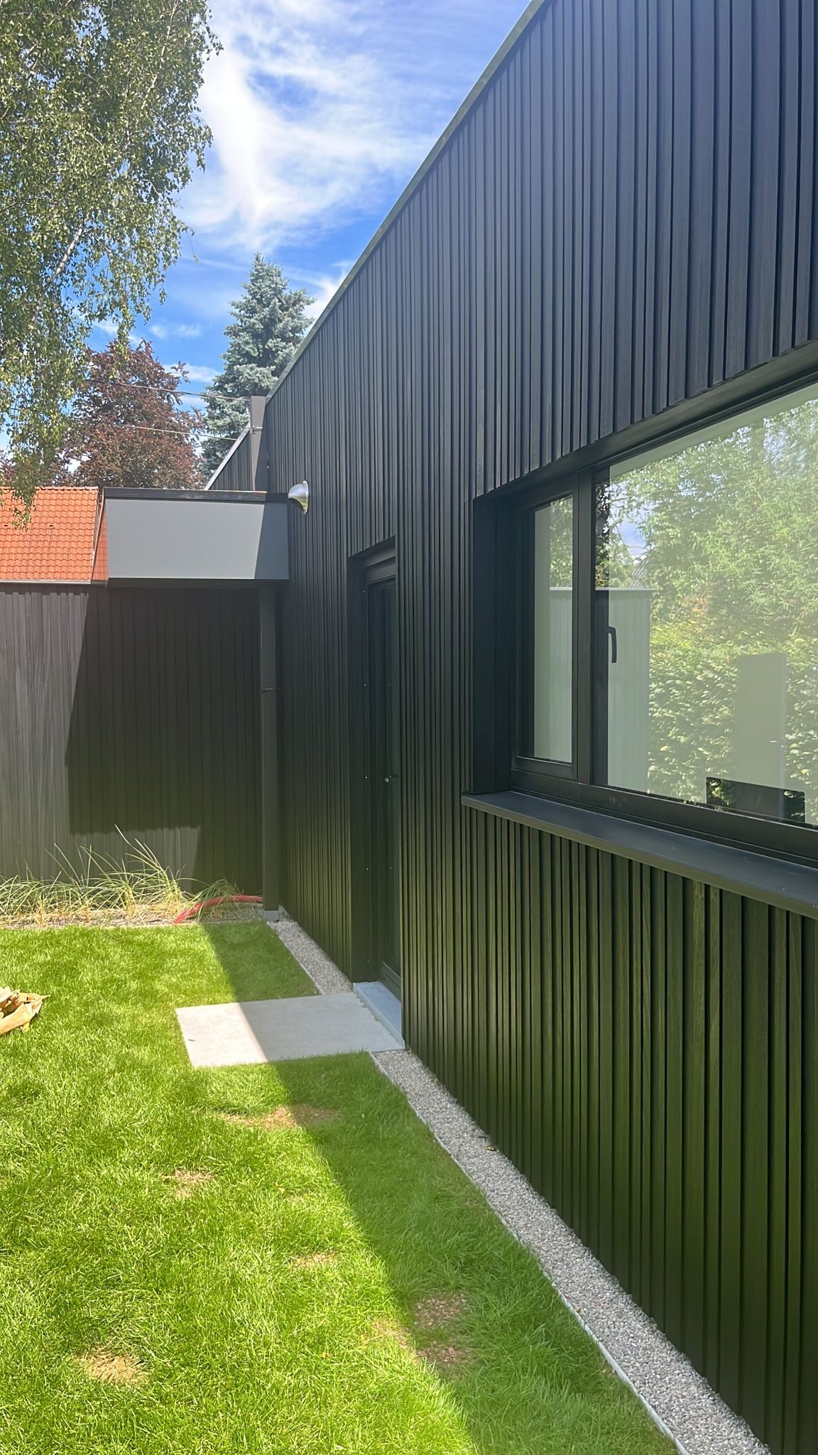Zwarte gevelbekleding langs een tuin