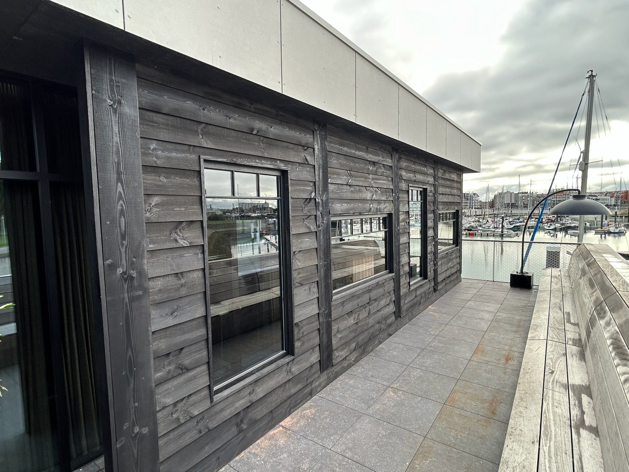 Zwarte houten gevelbekleding langs het terras van restaurant 't Werftje aan de haven in Zeebrugge